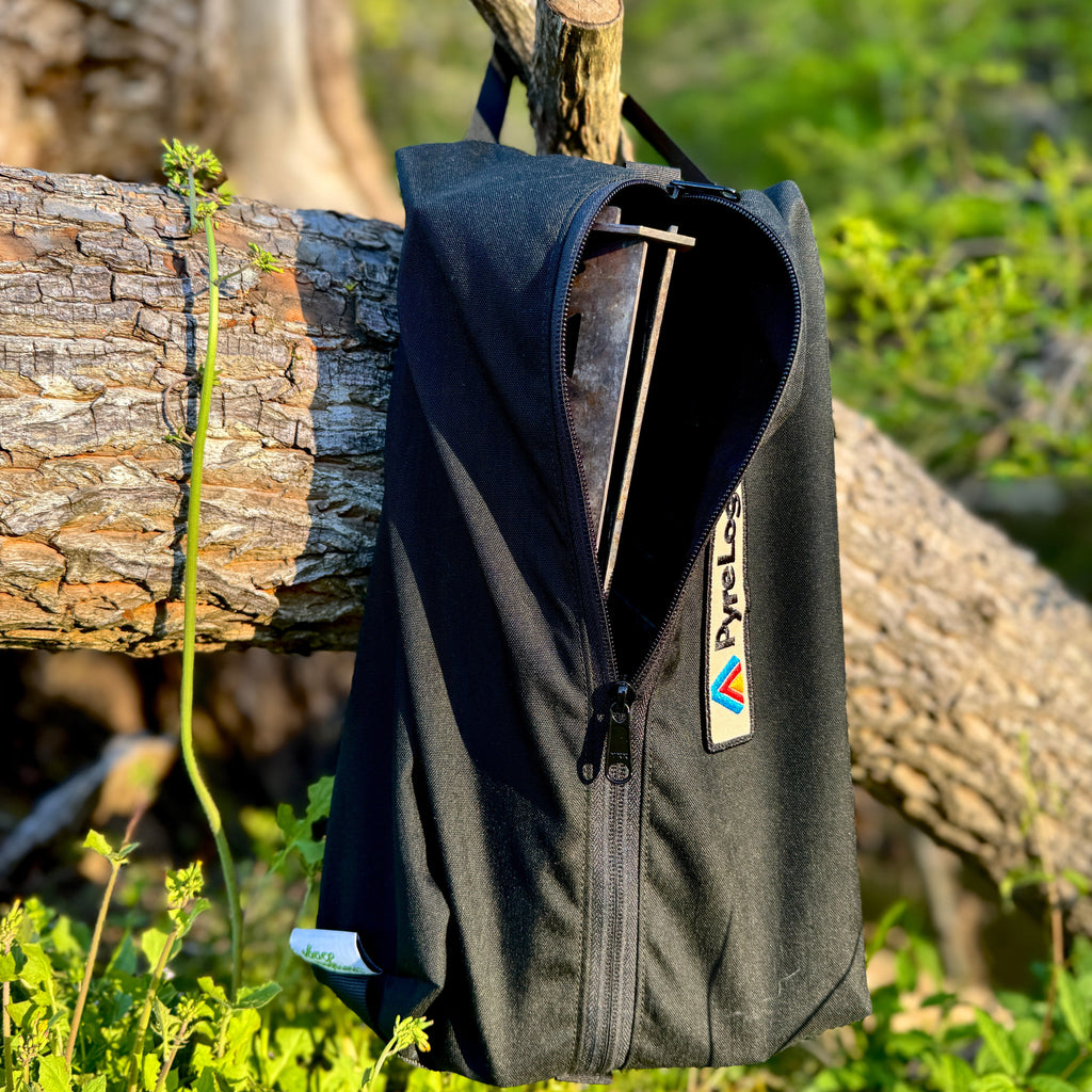 Black bag with a brand logo hanging on a tree branch in a natural setting