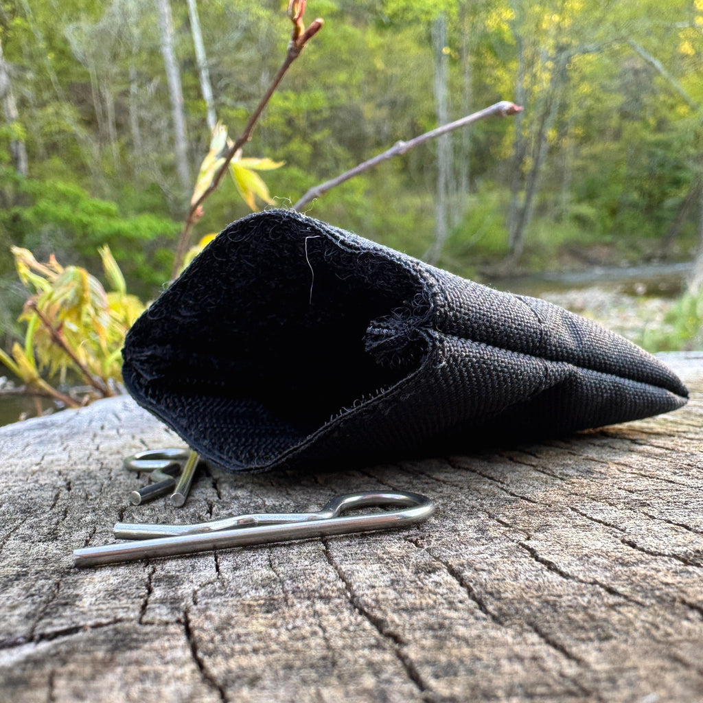 Black pin bag on a wooden log with a natural background