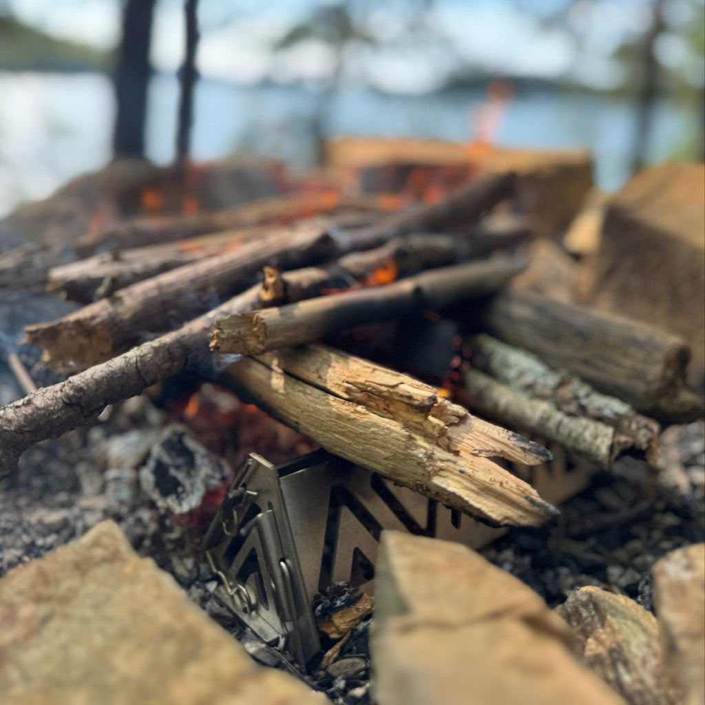 Firewood stacked in a fire pit with a blurred natural background