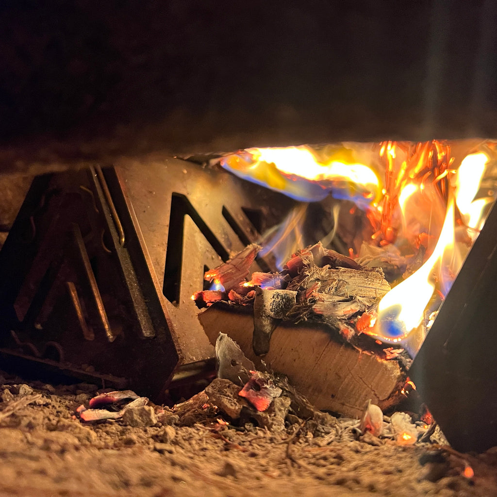 Close-up of a fire burning in a metal container with flames and glowing embers.